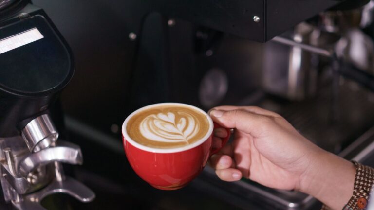 café saindo da cafeteira programável em uma xícara vermelha