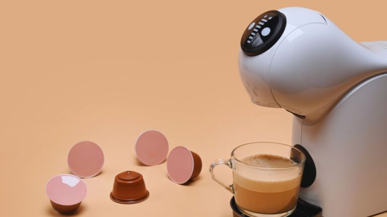 Cafeteira Dolce Gusto branca com cápsulas ao redor