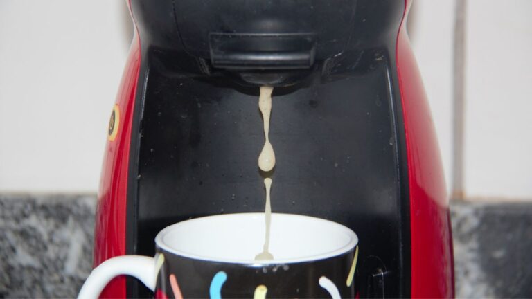 cafeteira vermelha e preta derramando café na xícara branca