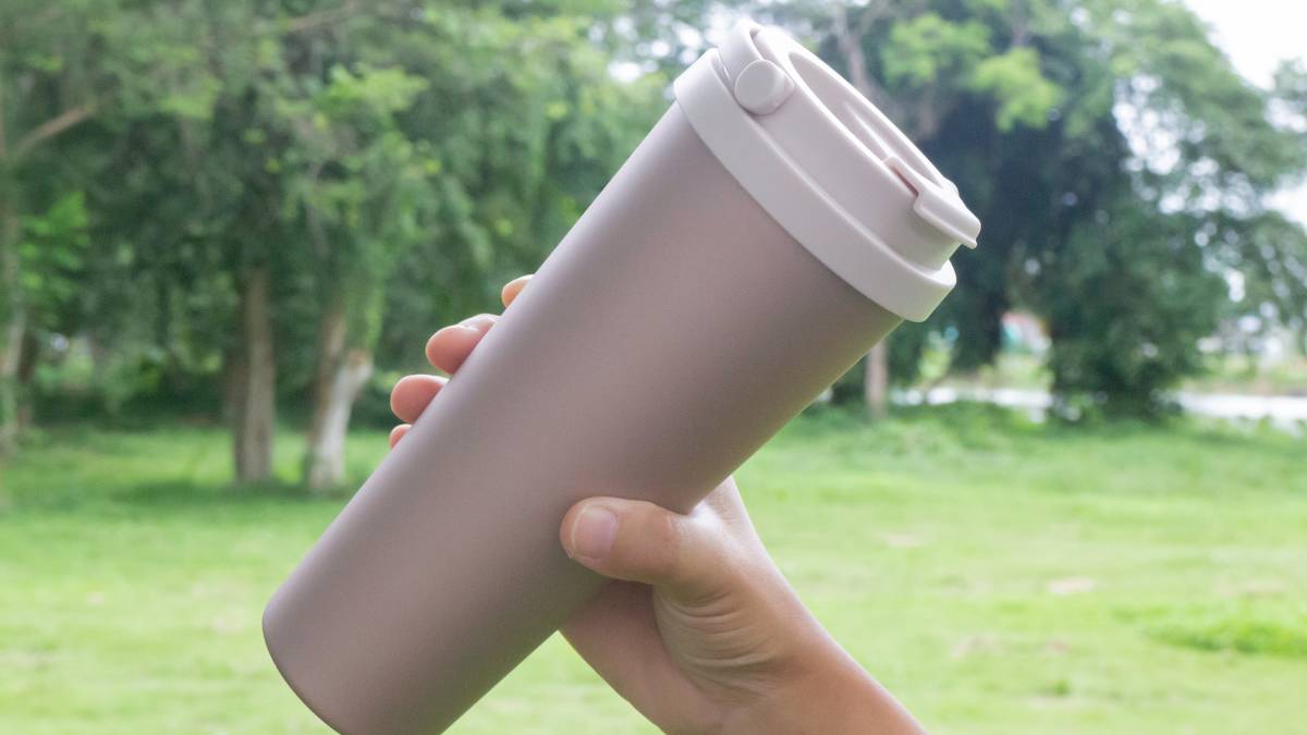 mão segurando copo térmico para café