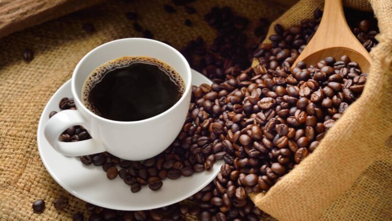 xicara de café com grãos em volta